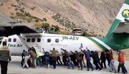 Passengers assist in pushing the plane off the runway to clear the path for an incoming aircr...jpeg